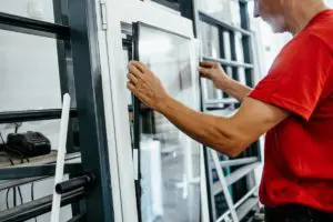Employé de menuiserie en train de poser un vitrage sur une fenêtre pvc blanche
