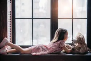 Petite fille installée devant une fenêtre