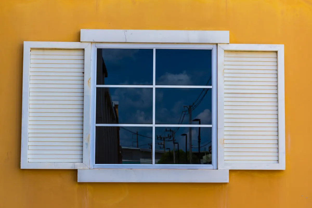 Fenêtre blanche avec croisillons sur un mur jaune